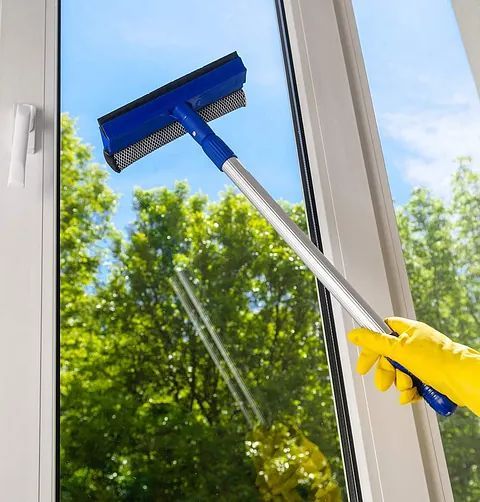 Una persona está limpiando una ventana con una escobilla de goma.