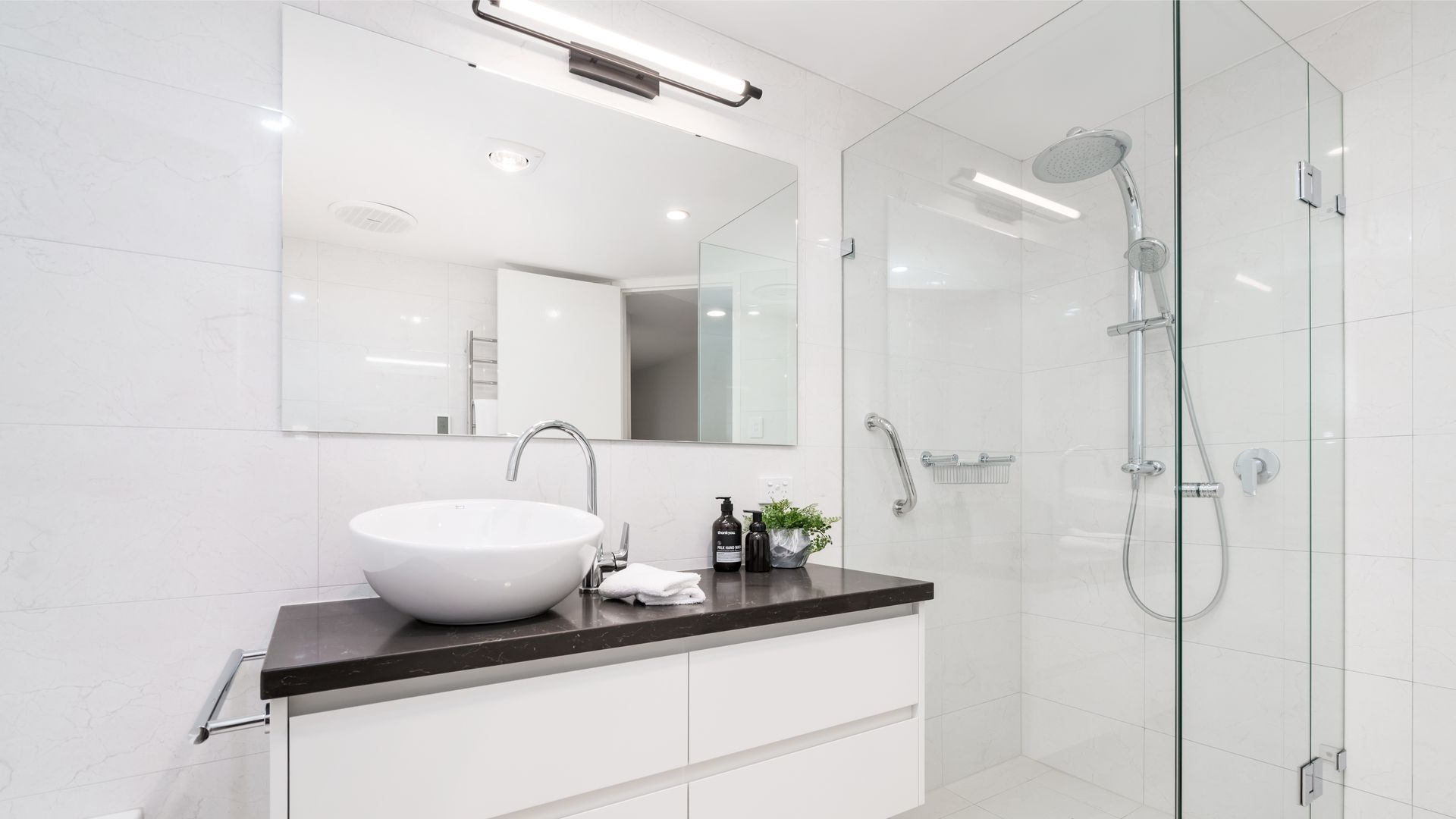 Un meuble et son vasque avec une douche et un miroir