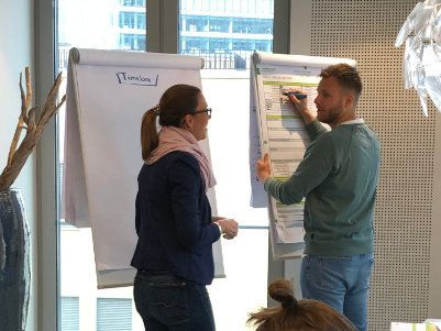 Ein Mann und eine Frau stehen vor einem Whiteboard.