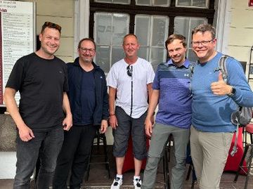 Eine Gruppe Männer posiert vor einem Gebäude für ein Foto.
