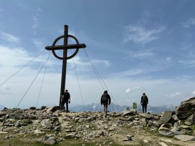 Ein Kreuz auf einem felsigen Hügel, um das herum Menschen stehen.