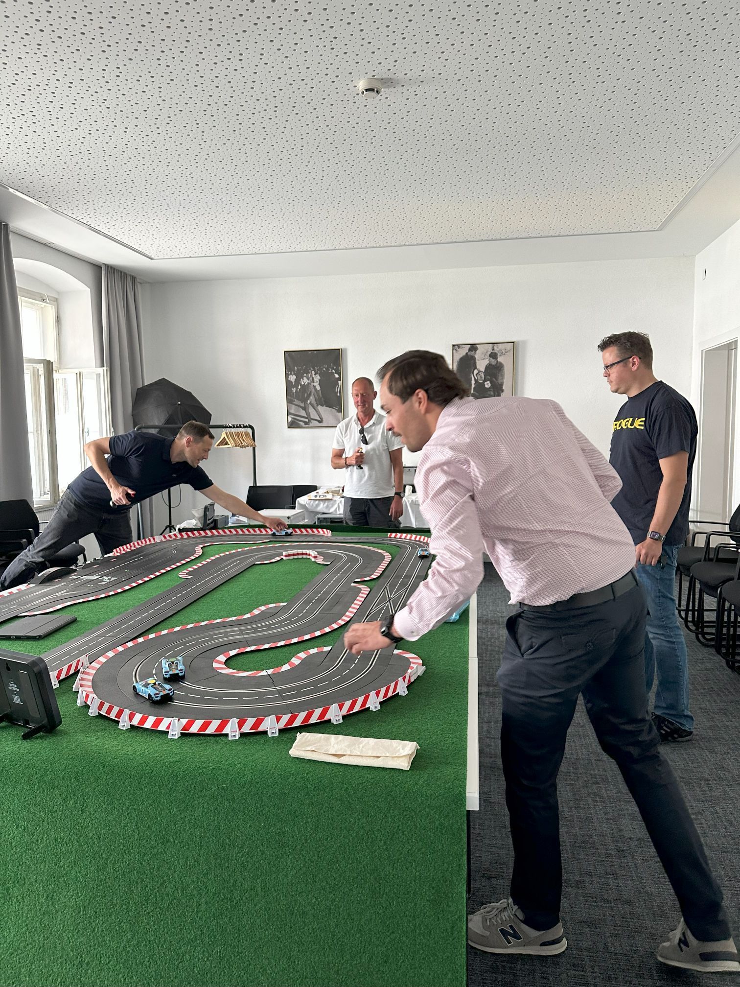 Eine Gruppe Männer spielt in einem Raum mit einer Spielzeug-Rennstrecke.