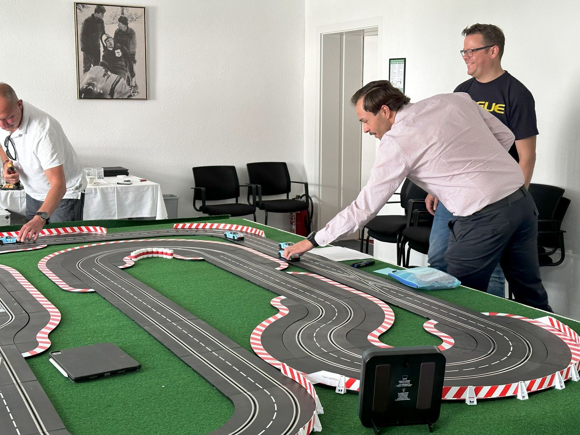 Ein Mann spielt auf einer Spielzeug-Rennstrecke
