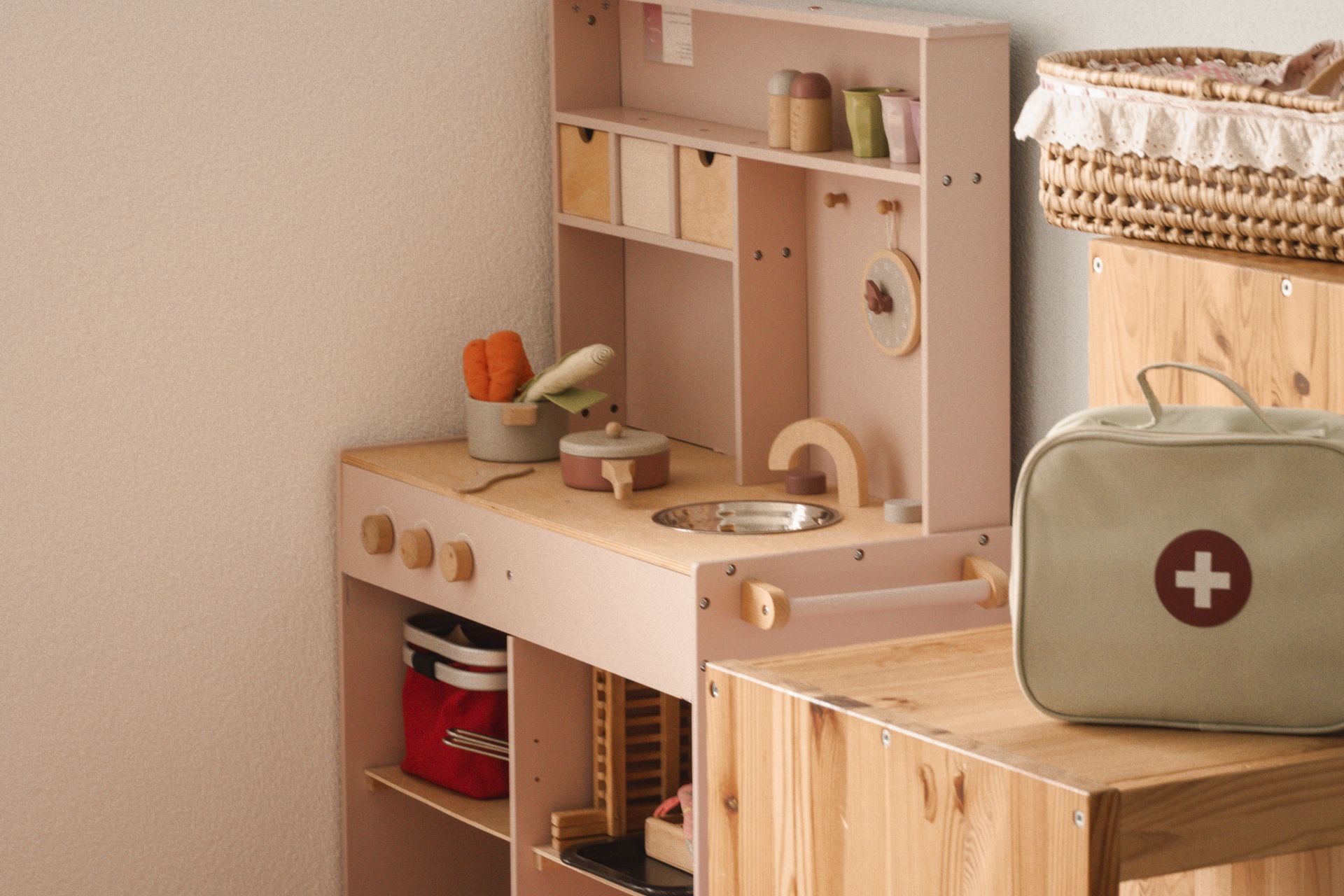 Eine Spielküche aus Holz mit einem Erste-Hilfe-Kasten auf einem Holztisch.