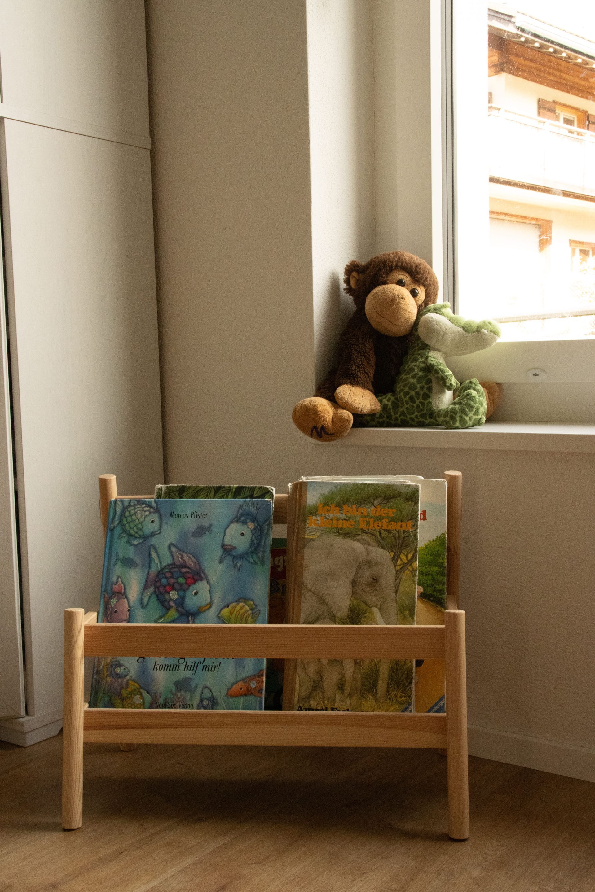 Ein Affe und ein Frosch sitzen auf einem Fensterbrett neben einem Bücherregal.