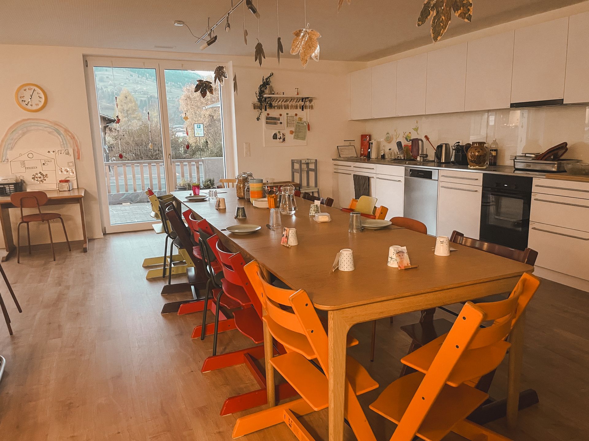 Eine Küche mit einem langen Tisch und Stühlen und einer Uhr an der Wand.