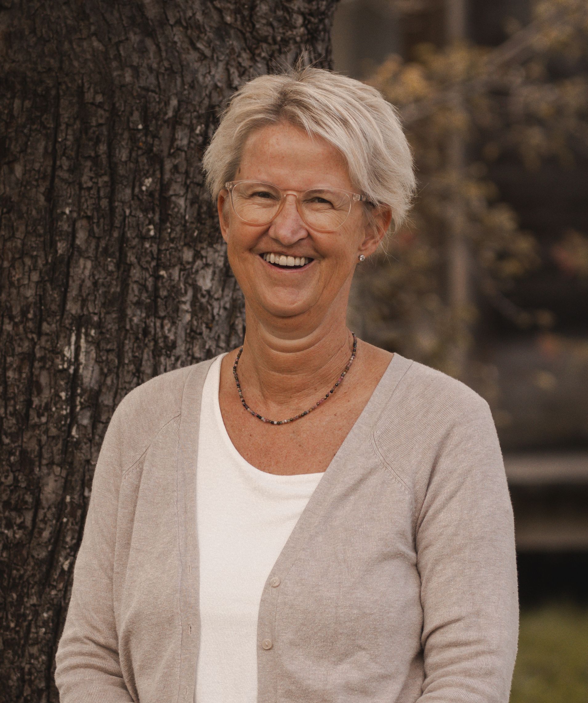 Eine Frau in einem gestreiften Hemd steht vor einer Holzwand.