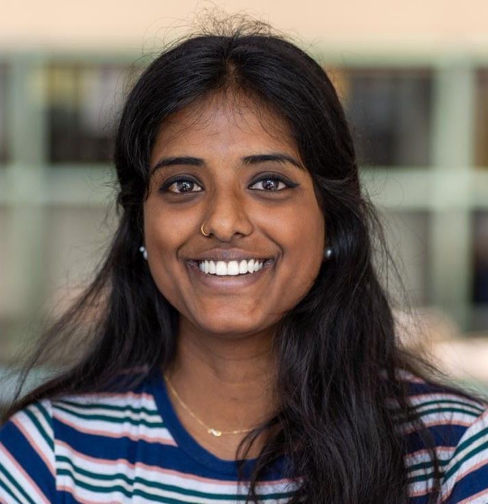 Eine Frau in einem gestreiften Hemd lächelt in die Kamera.