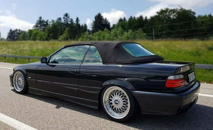 Ein schwarzes E36 BMW-Cabrio steht am Straßenrand.
