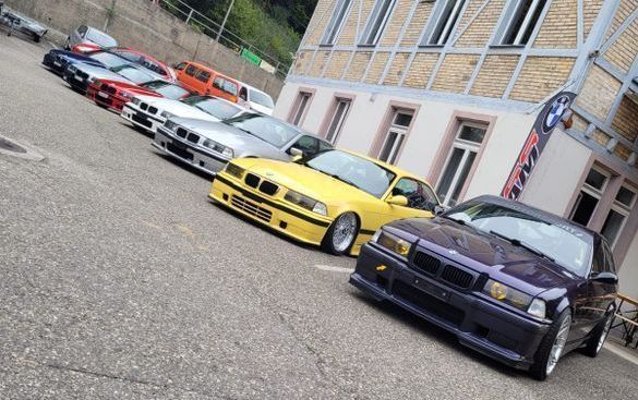 Vor einem Gebäude parken mehrere Autos.