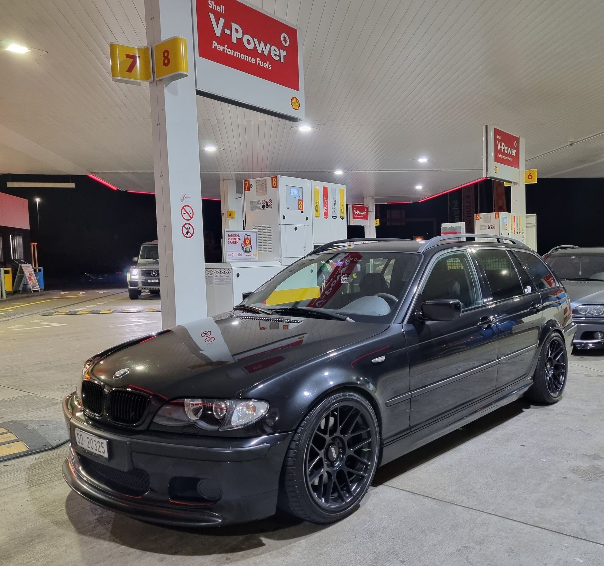 Ein schwarzes Auto steht vor einer V-Power-Tankstelle