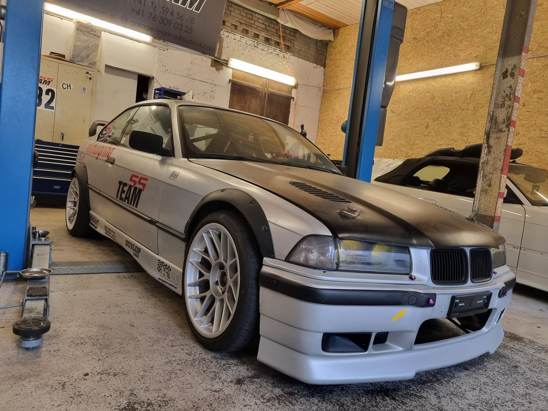 Ein silberner BMW steht auf einer Hebebühne in einer Garage.