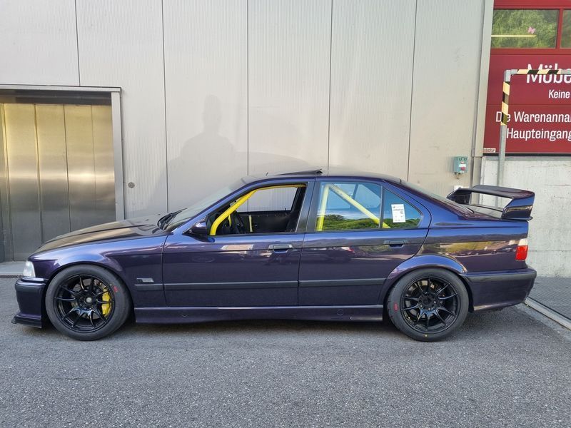 Vor einem Gebäude parkt ein lila Auto.