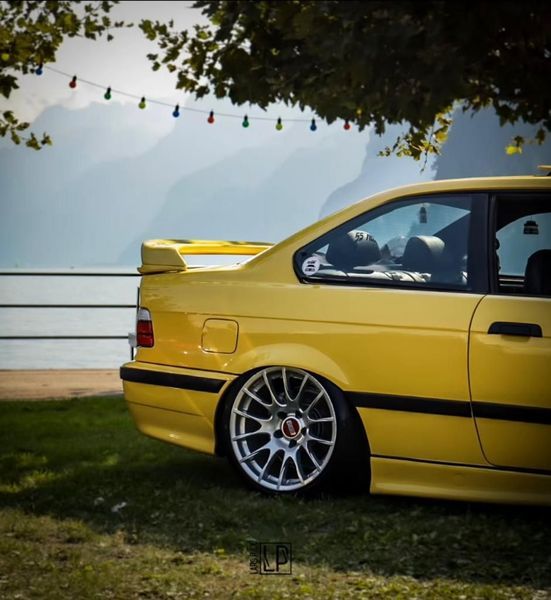 Ein gelbes Auto ist unter einem Baum in der Nähe eines Gewässers geparkt
