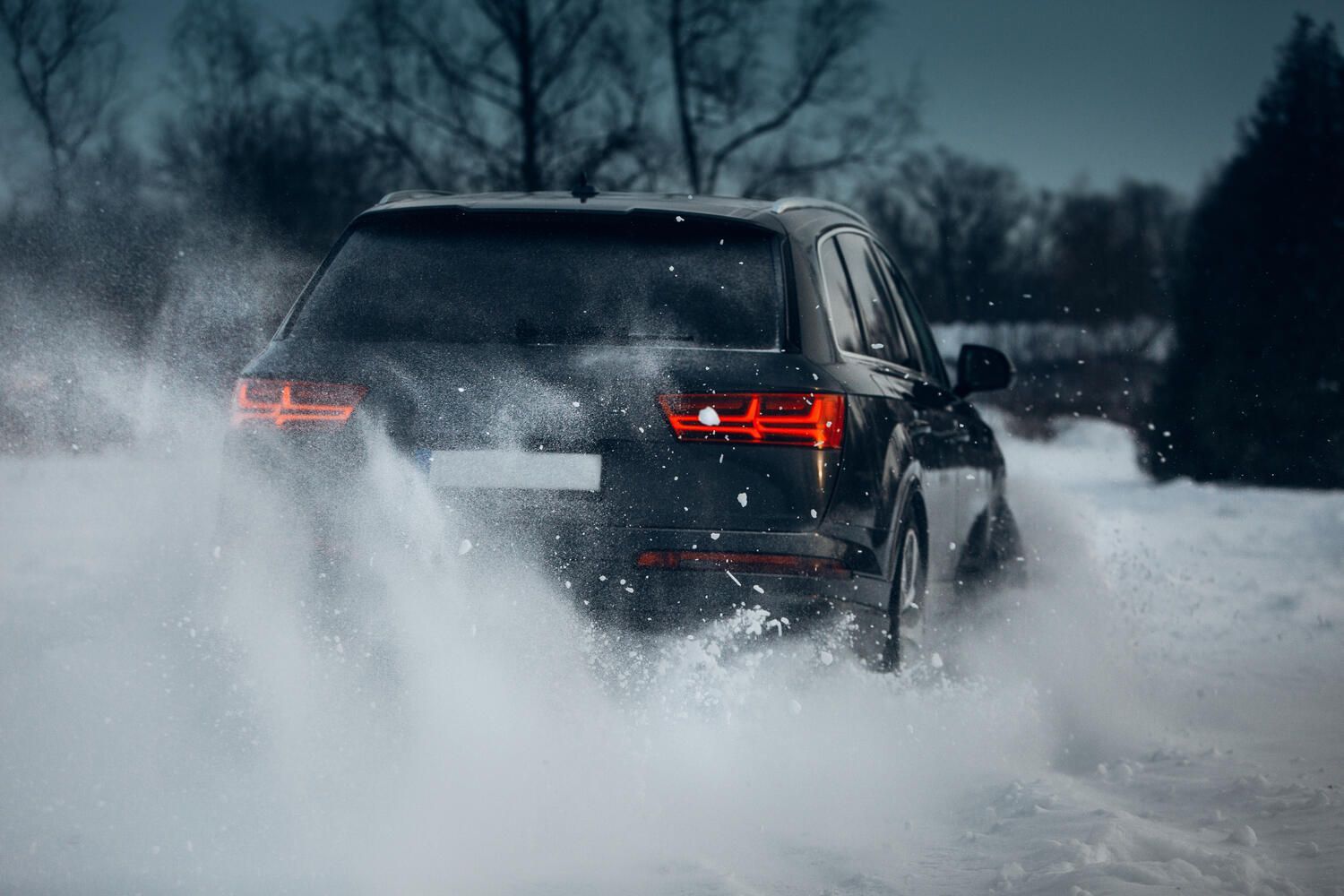 Ein Auto fährt nachts durch den Schnee.