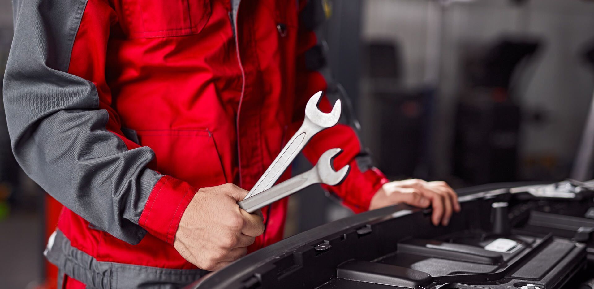 Ein Mechaniker arbeitet mit einem Schraubenschlüssel an einem Auto.