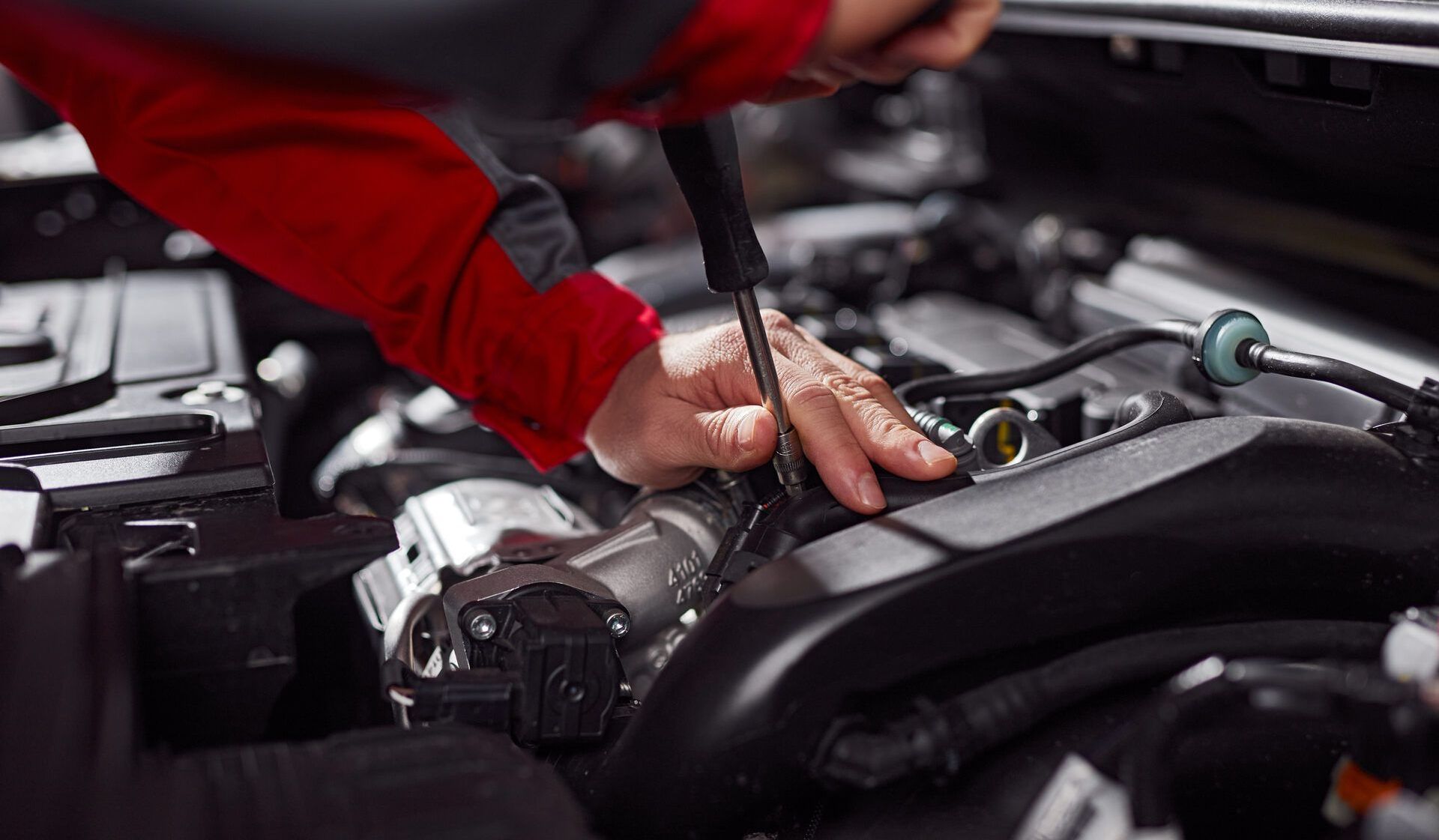 Ein Mechaniker arbeitet mit einem Schraubenzieher an einem Automotor.