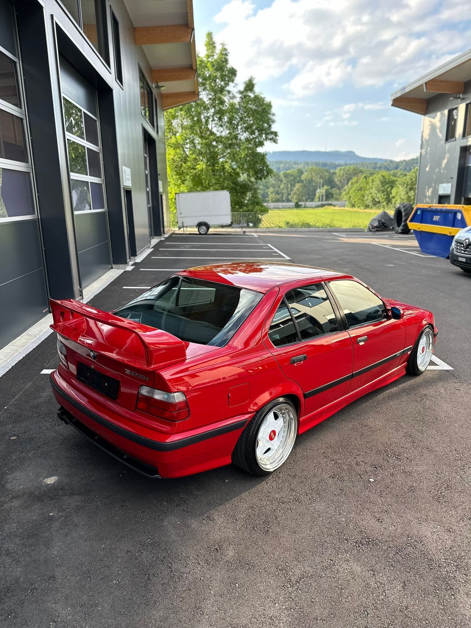 Ein rotes Auto steht auf einem Parkplatz vor einem Gebäude.