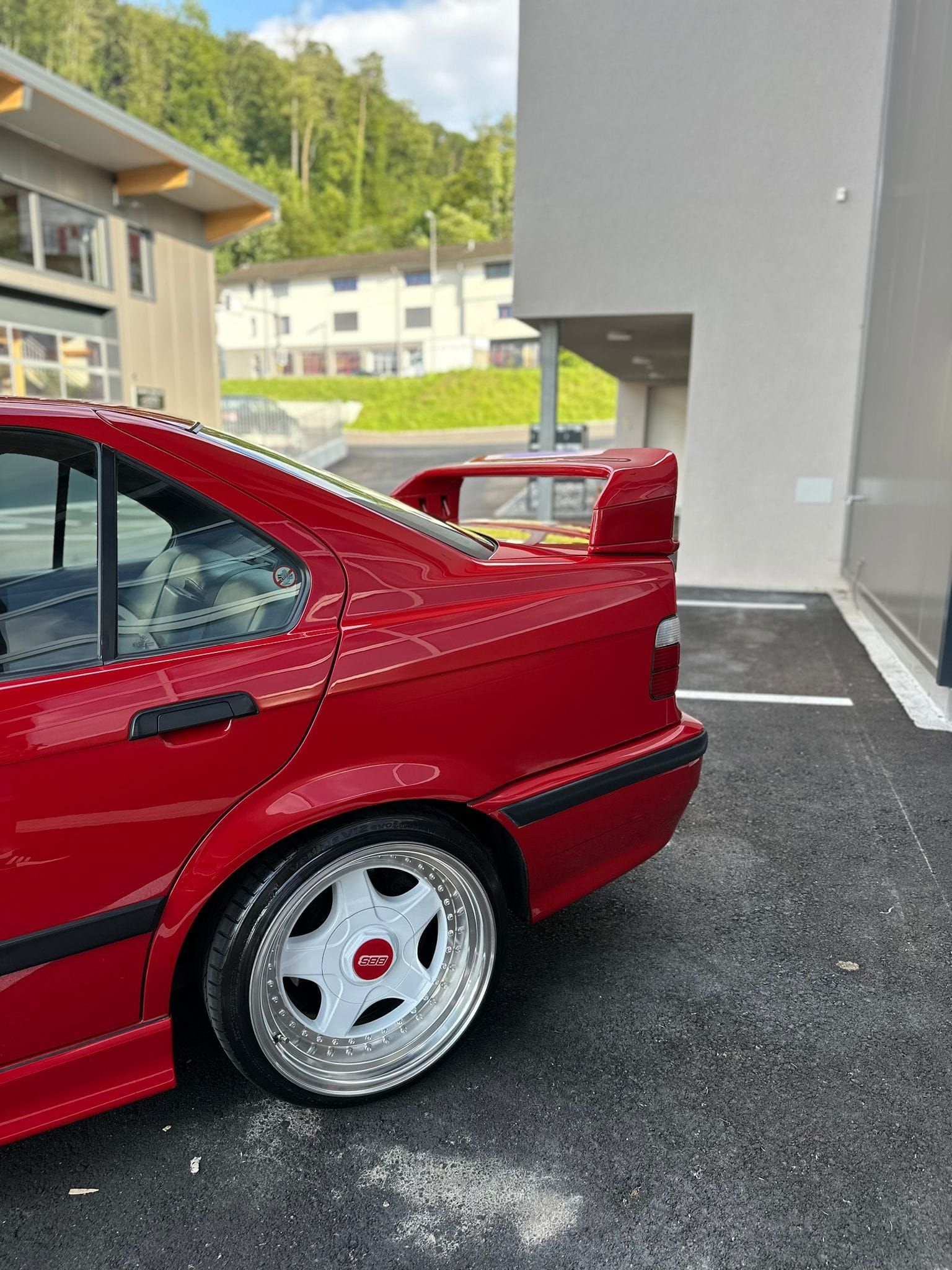 Ein rotes Auto steht auf einem Parkplatz vor einem Gebäude.