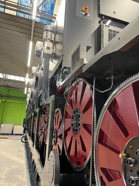 Un primer plano de una máquina con ruedas rojas en una fábrica.