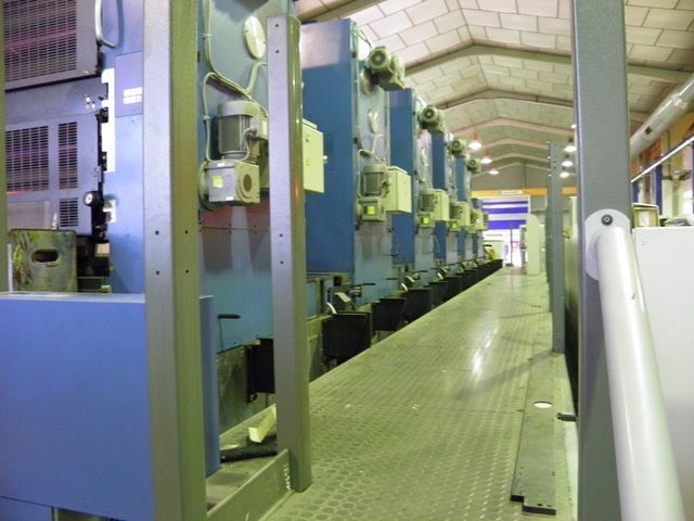 Una fila de máquinas azules están alineadas en una fábrica