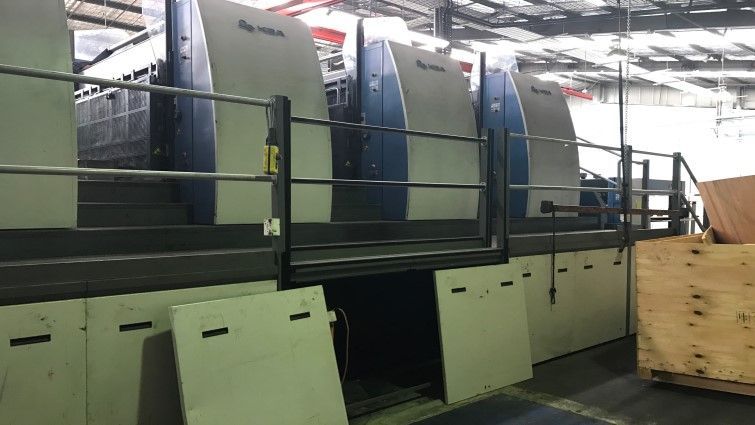 Una máquina de impresión está en un almacén al lado de una caja de madera.