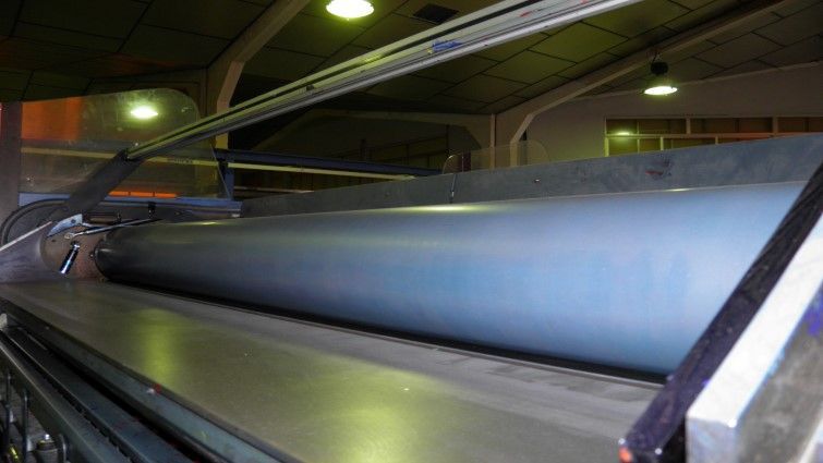 Un rodillo grande está colocado encima de una cinta transportadora en una fábrica.