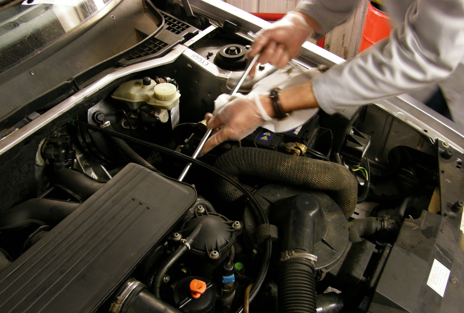 Les mains d'un mécanicien utilisant une clé pour travailler sur un moteur de voiture.