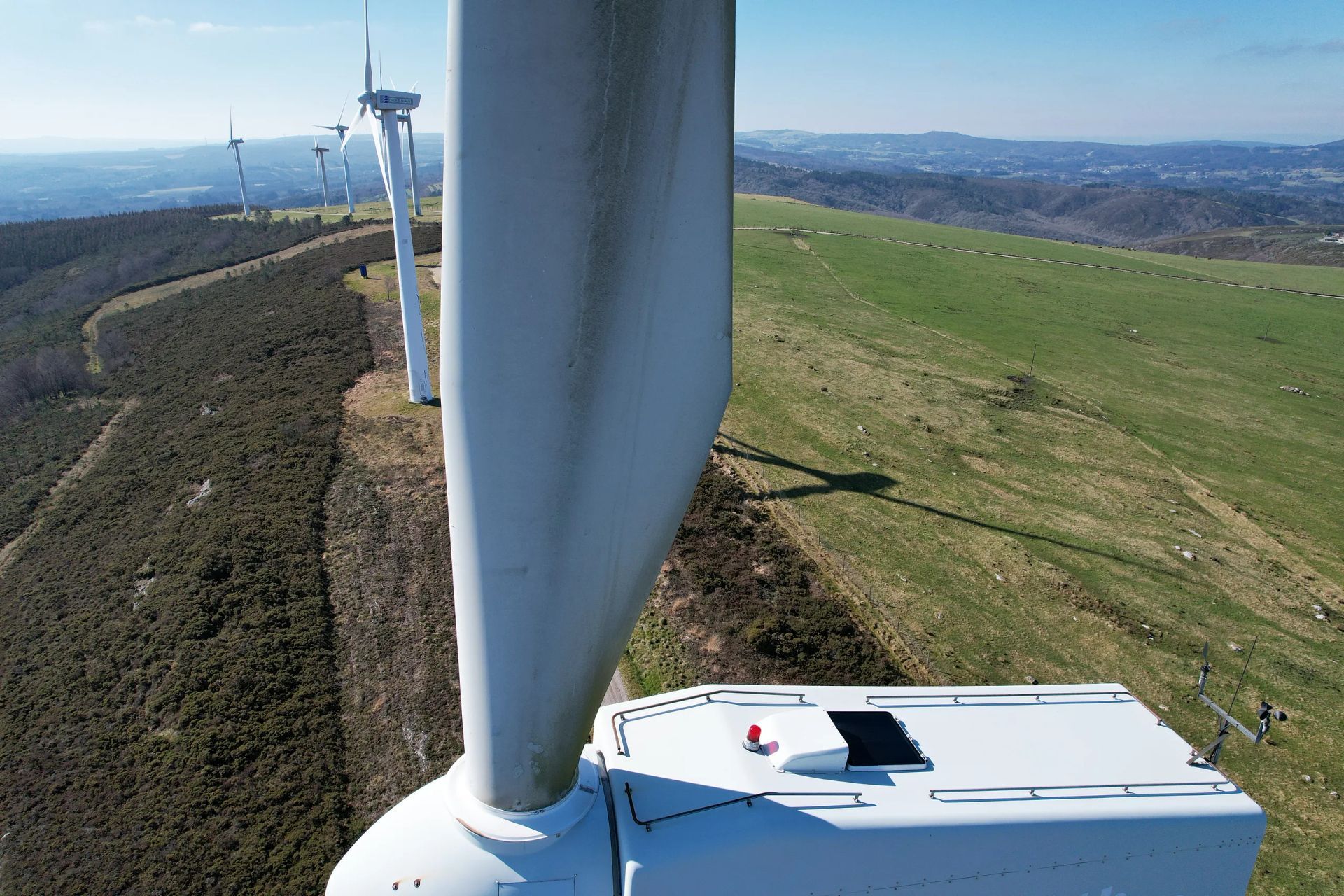 Una vista aérea de una turbina eólica en la cima de una colina cubierta de hierba.