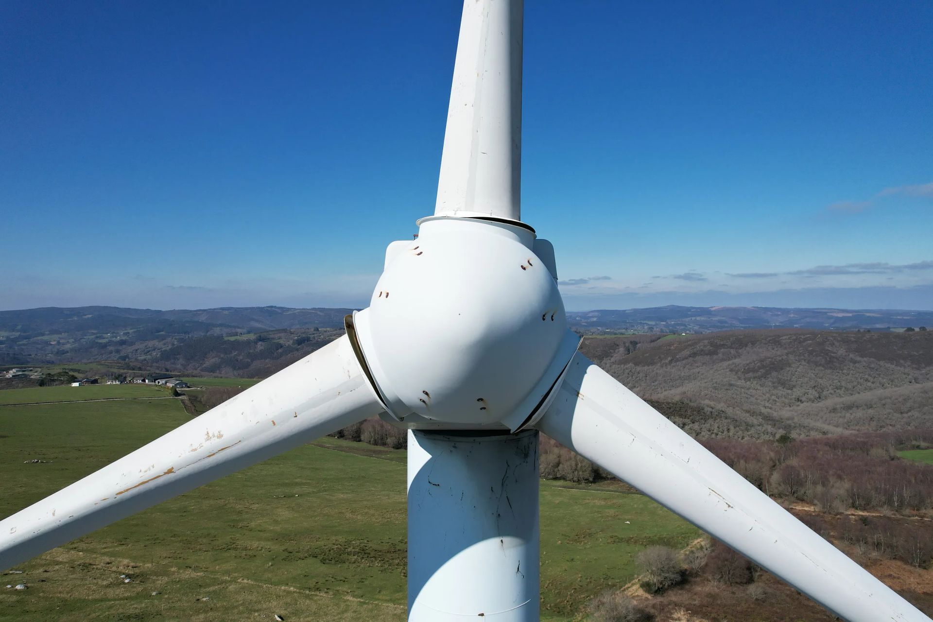 Un aerogenerador en un campo con montañas al fondo