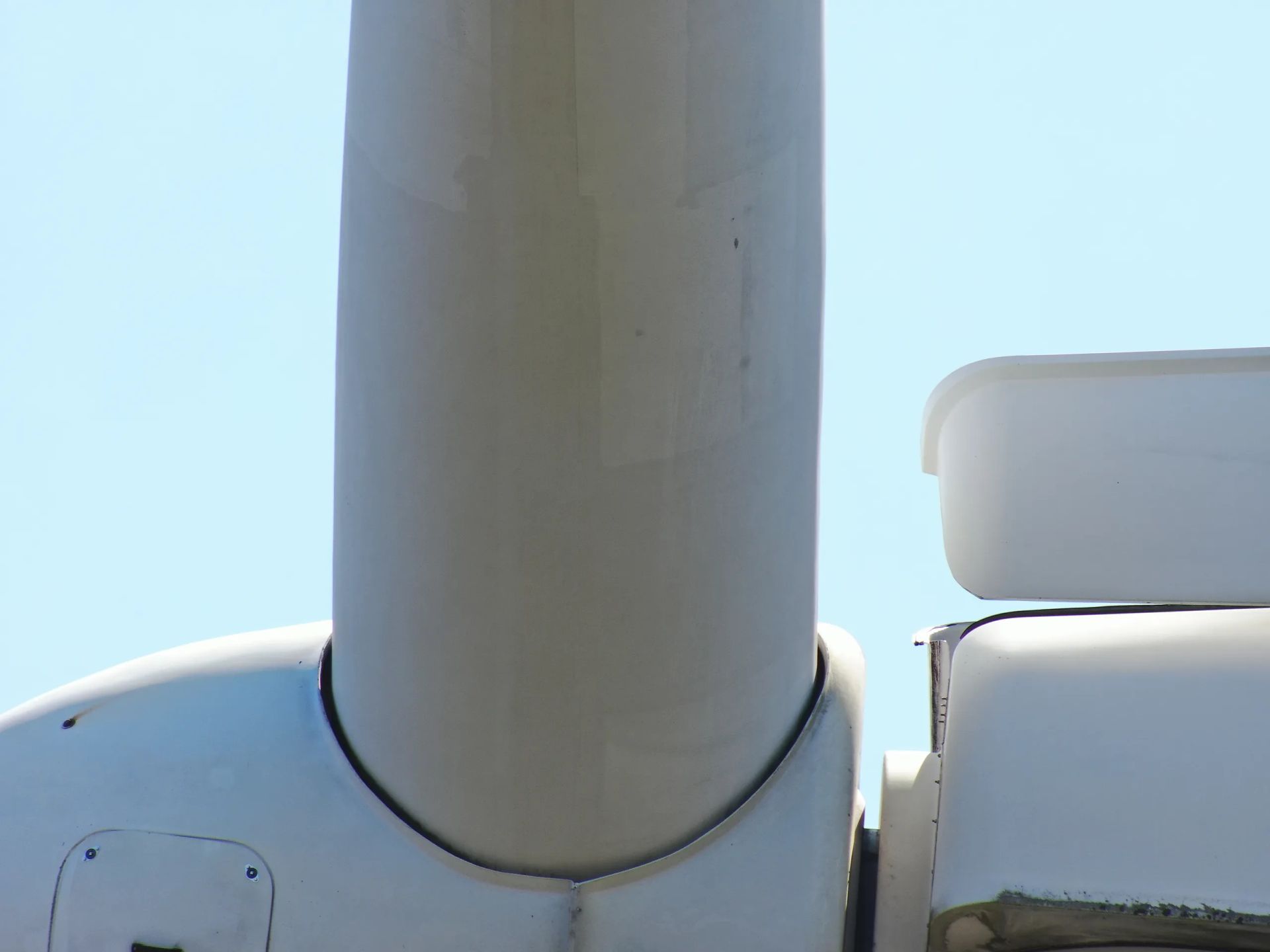 Un primer plano de una turbina eólica con un cielo azul de fondo.