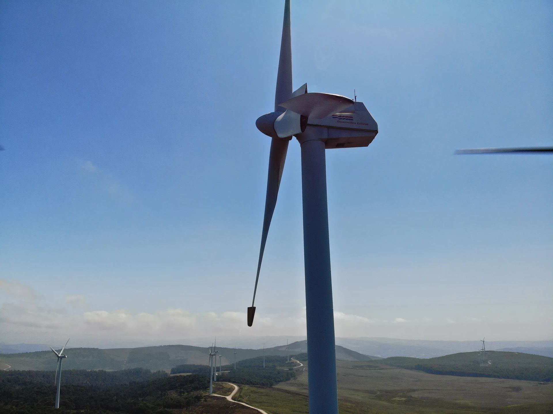 Una turbina eólica con una pala rota en la cima de una colina