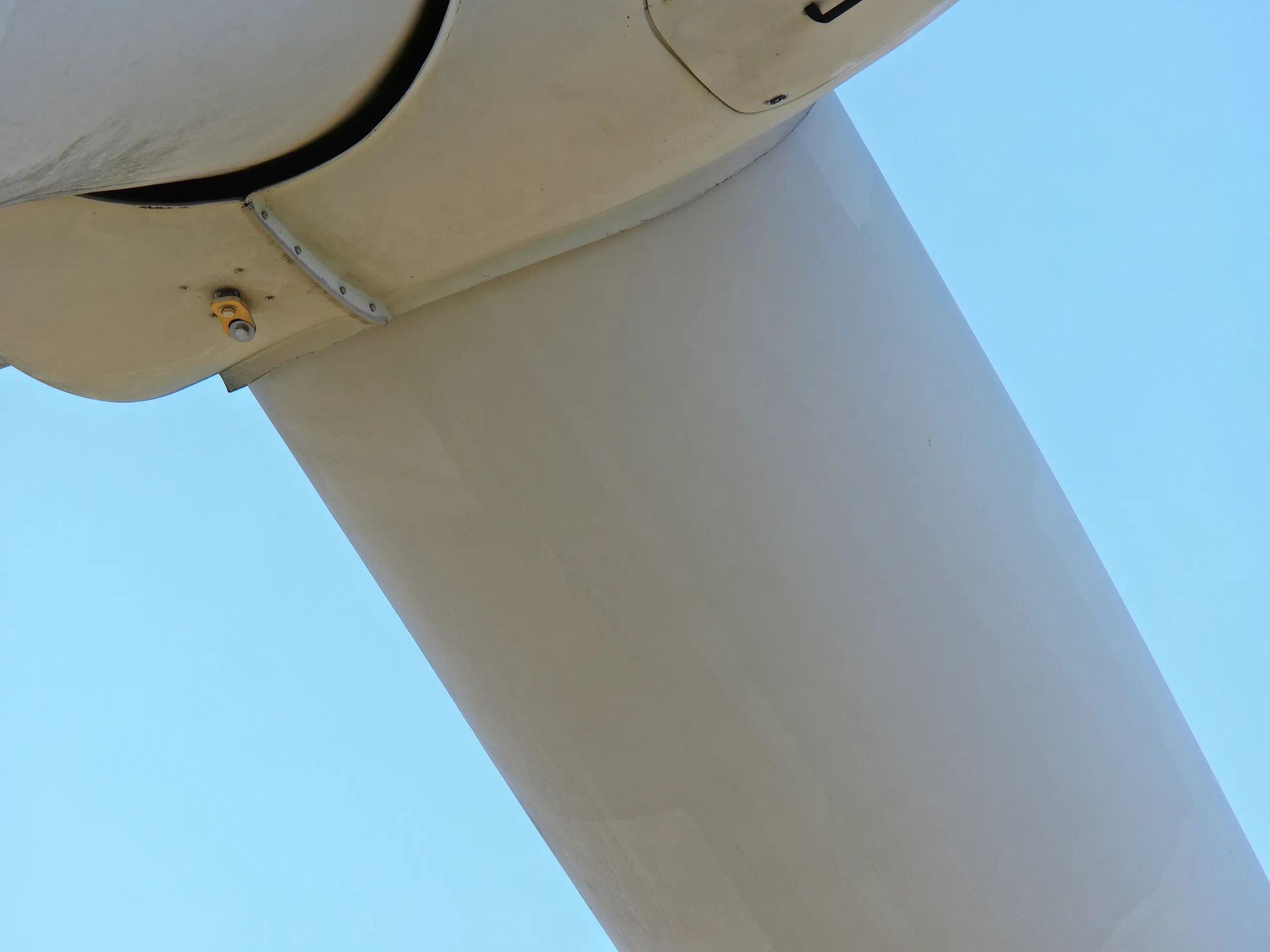 Un primer plano de una turbina eólica contra un cielo azul.