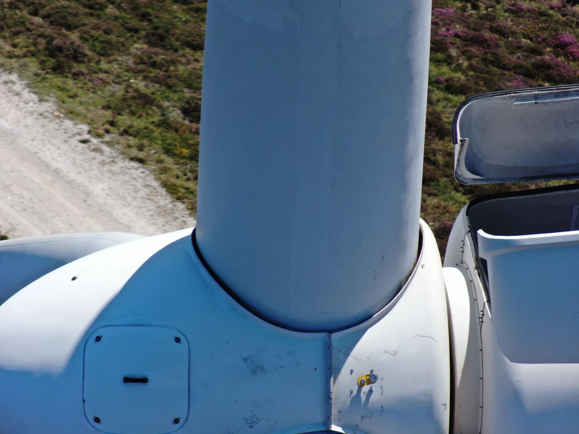 Una turbina eólica se encuentra encima de un camino de tierra.