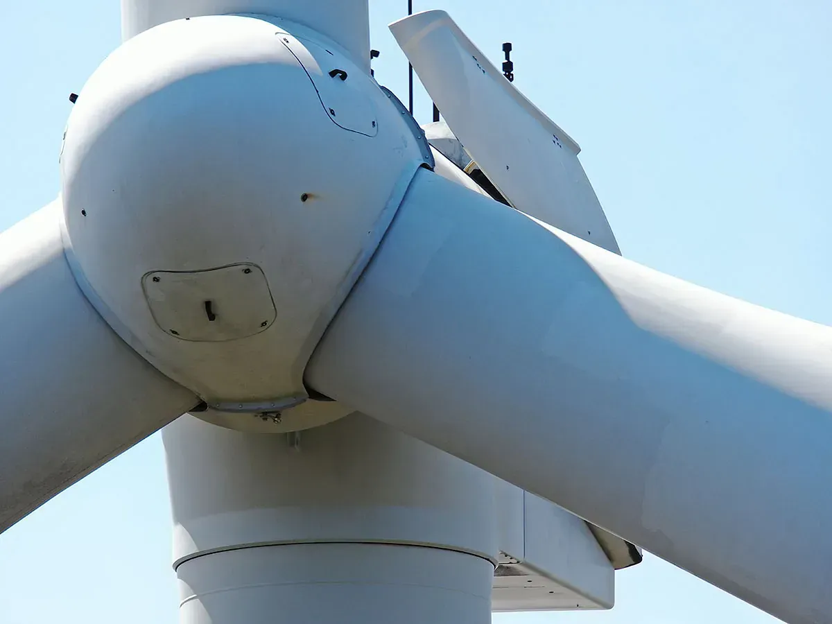 Un primer plano de una turbina eólica con un cielo azul de fondo.