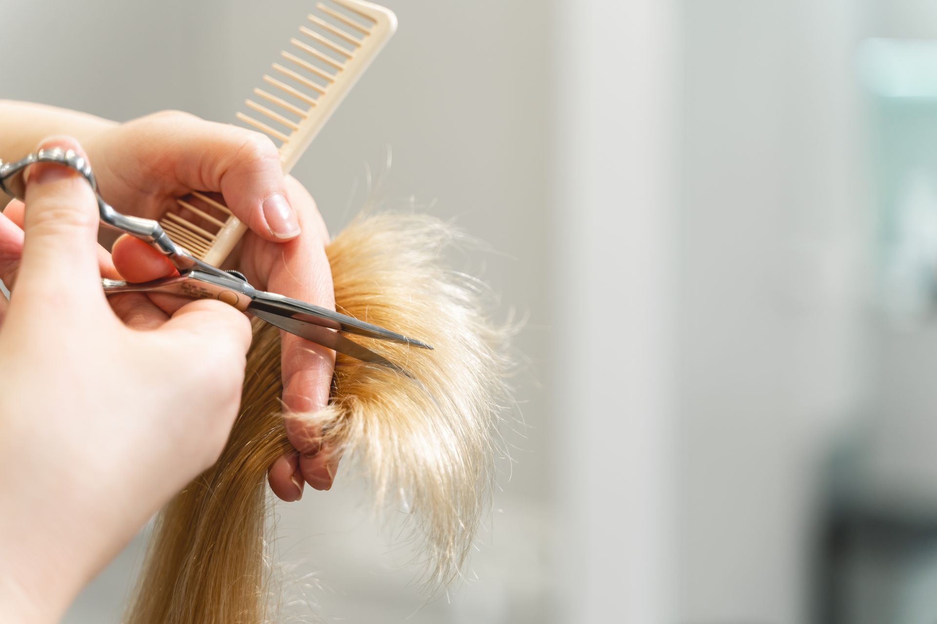 Ein Friseur glättet das braune Haar einer Kundin in einem Salon mit einem Glätteisen. Die Kundin sitzt auf einem Stuhl.