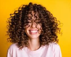 Frau mit braunem Haar, das zu einer eleganten Hochsteckfrisur gestylt und mit einer dekorativen Haarspange befestigt ist.