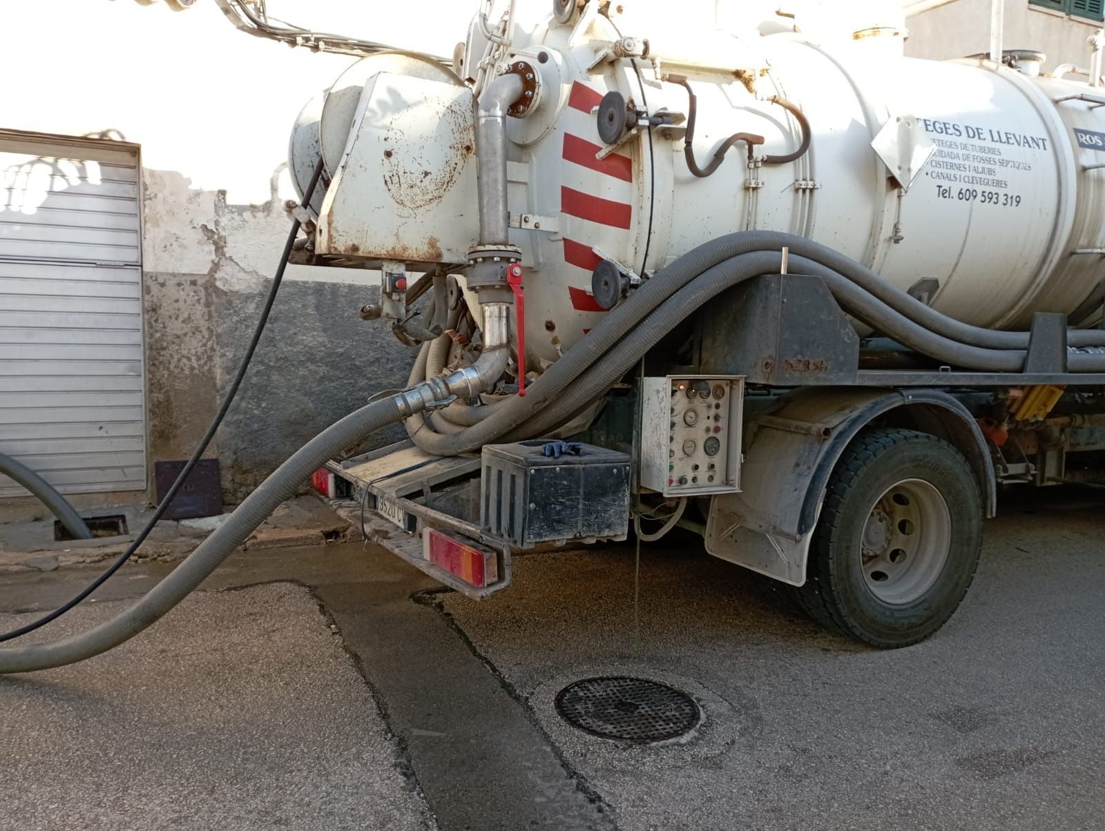 Un camión de vacío blanco está estacionado al costado de la carretera.