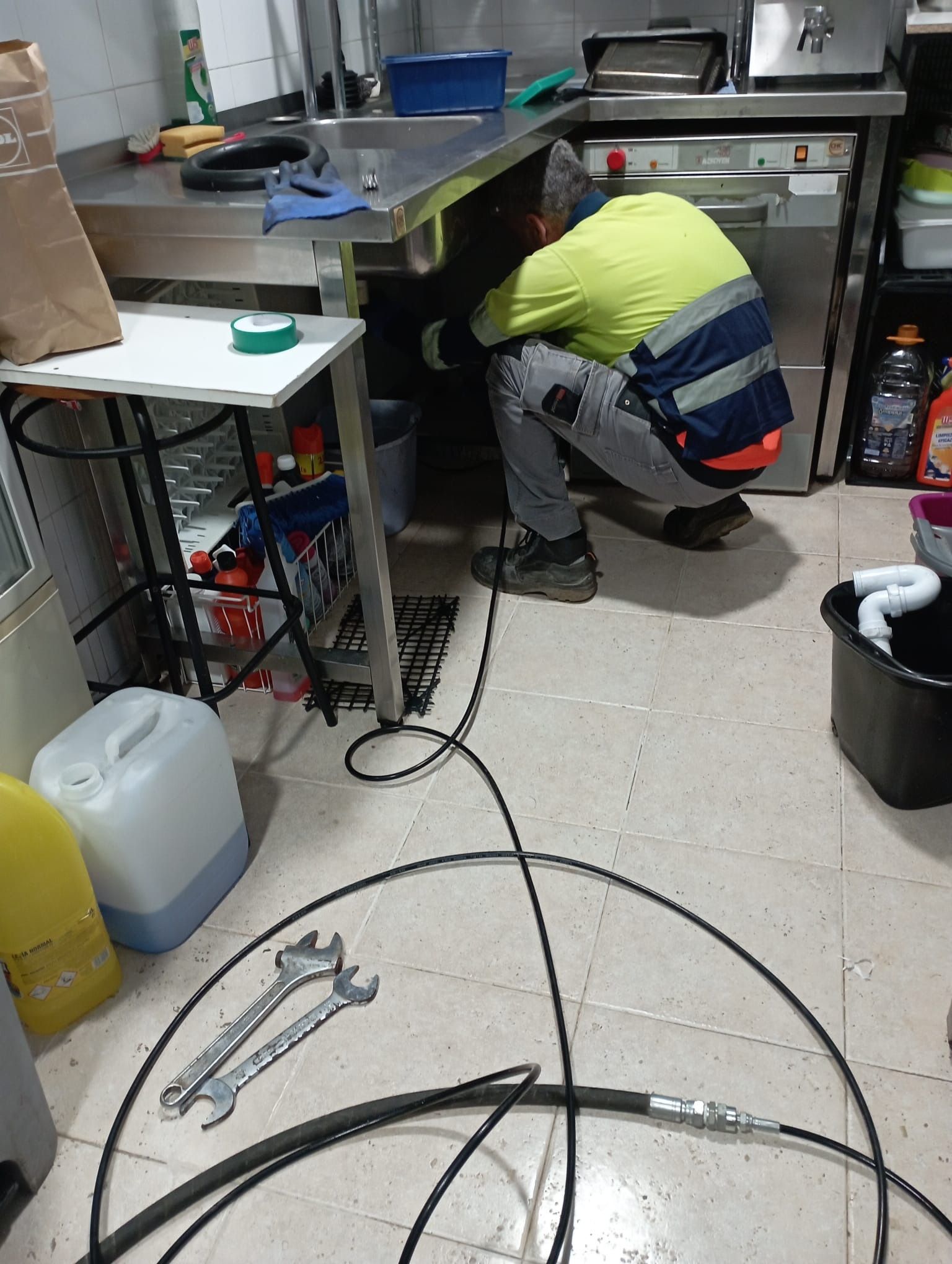 Un hombre está trabajando debajo de un fregadero en una cocina.