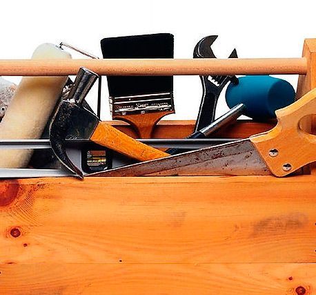 Una caja de herramientas de madera llena de herramientas, incluida una sierra y un martillo.