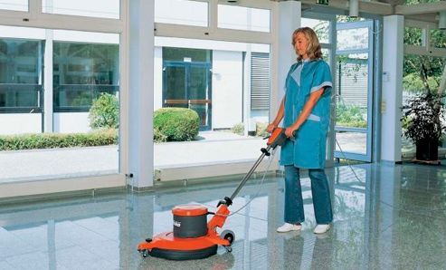 Una mujer está limpiando el suelo con una máquina.