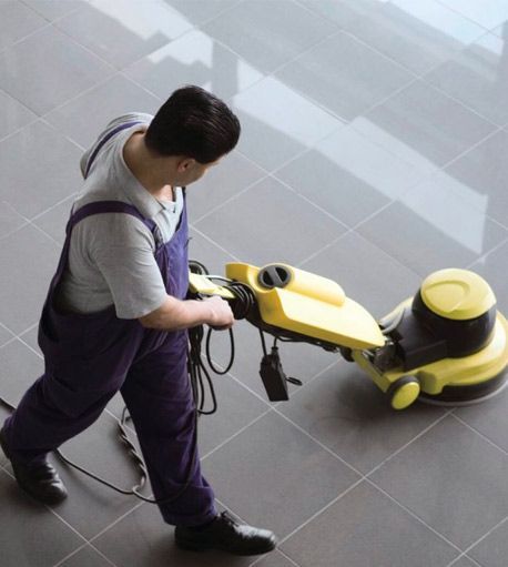 Un hombre está usando una máquina para limpiar un piso de baldosas.
