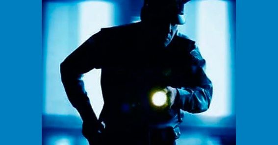 Una silueta de un oficial de policía sosteniendo una linterna.