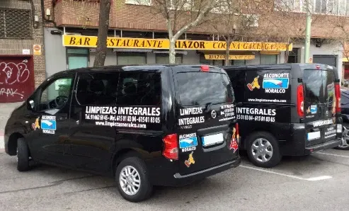 Dos furgonetas negras están estacionadas frente a un restaurante.