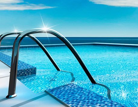 Una piscina con escaleras que conducen a ella y el océano al fondo.