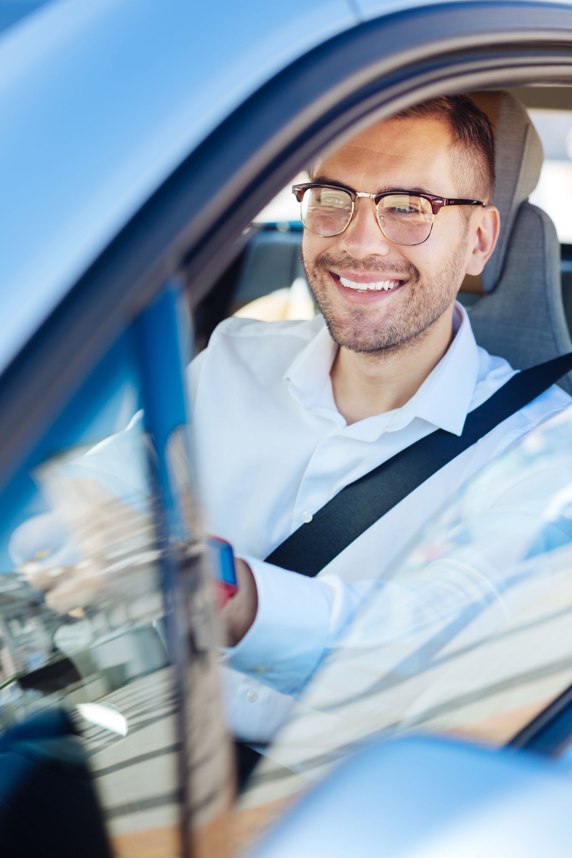 Jeune homme souriant au volant d'une voiture