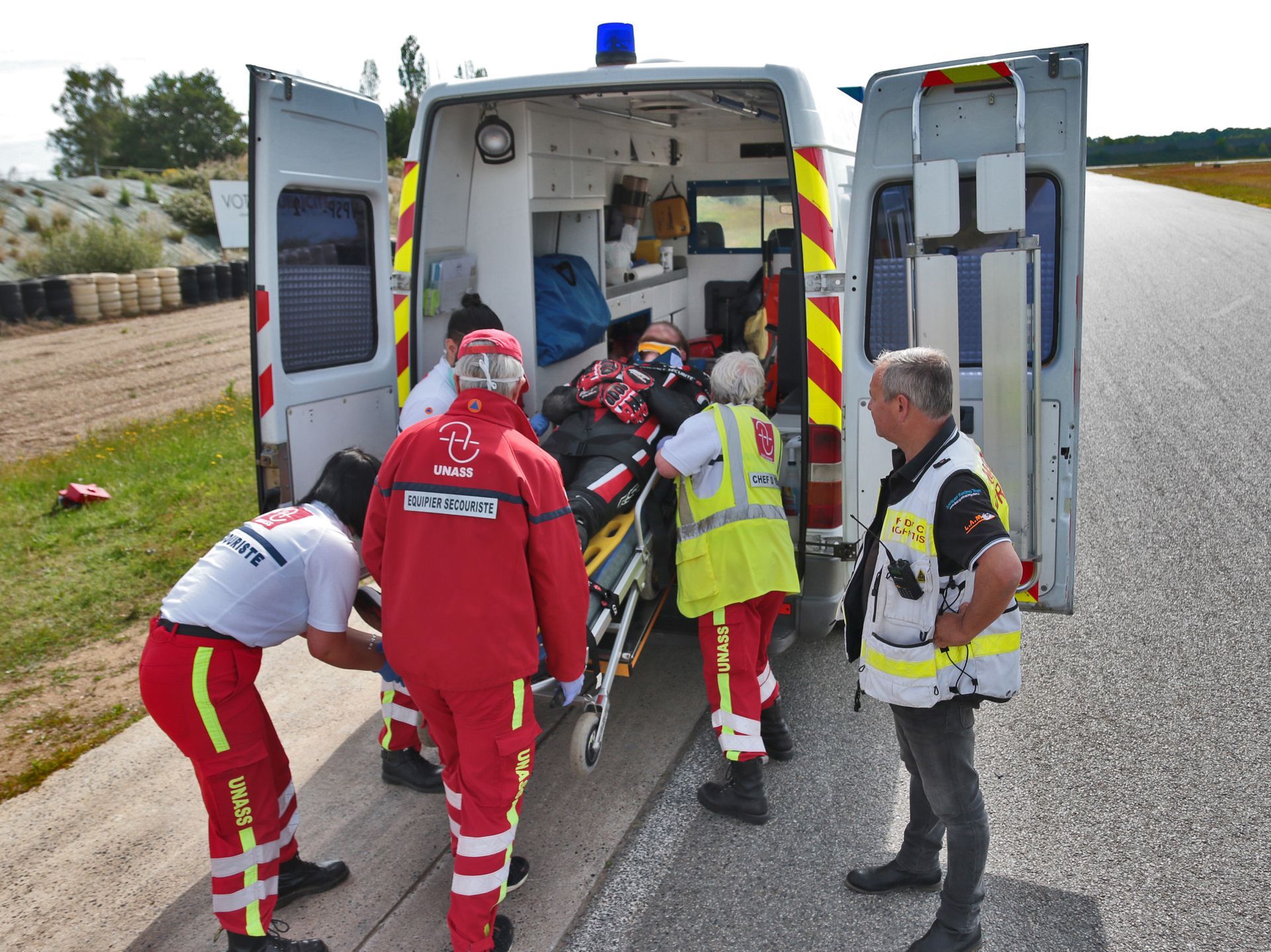 Mise d'un brancard dans une ambulance par une équipe de secouristes