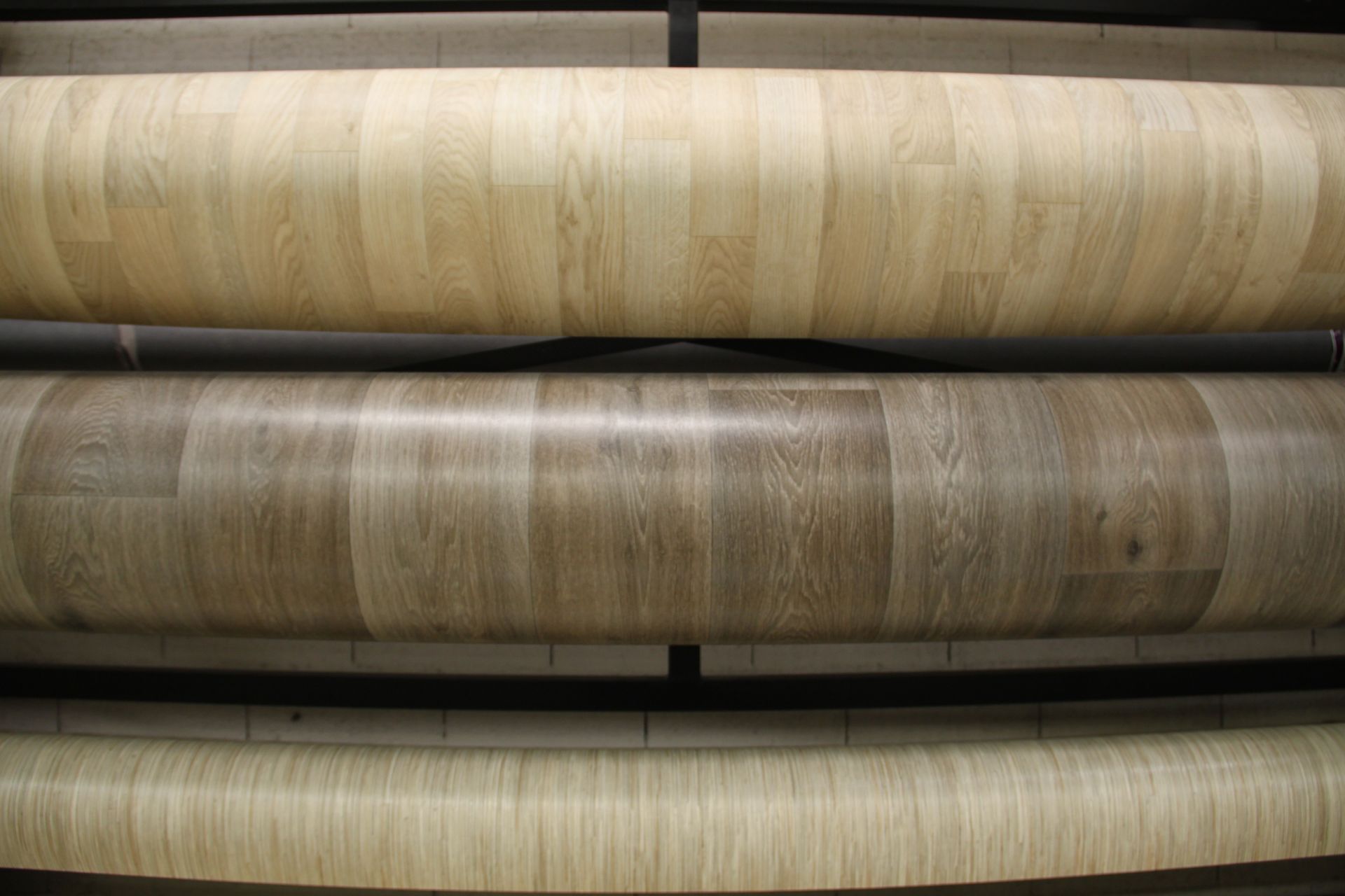 Trois grands rouleaux de revêtement de sol en vinyle à motifs ou en linoléum empilés horizontalement