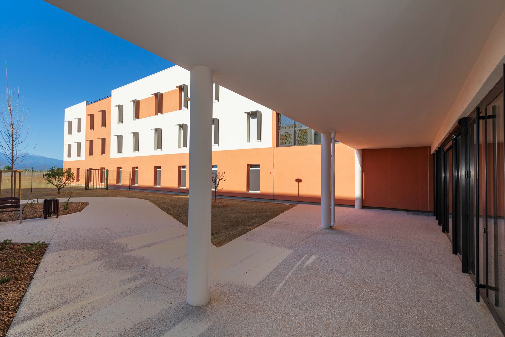 Cour intérieure d'un immeuble moderne avec allée couverte, colonnes blanches