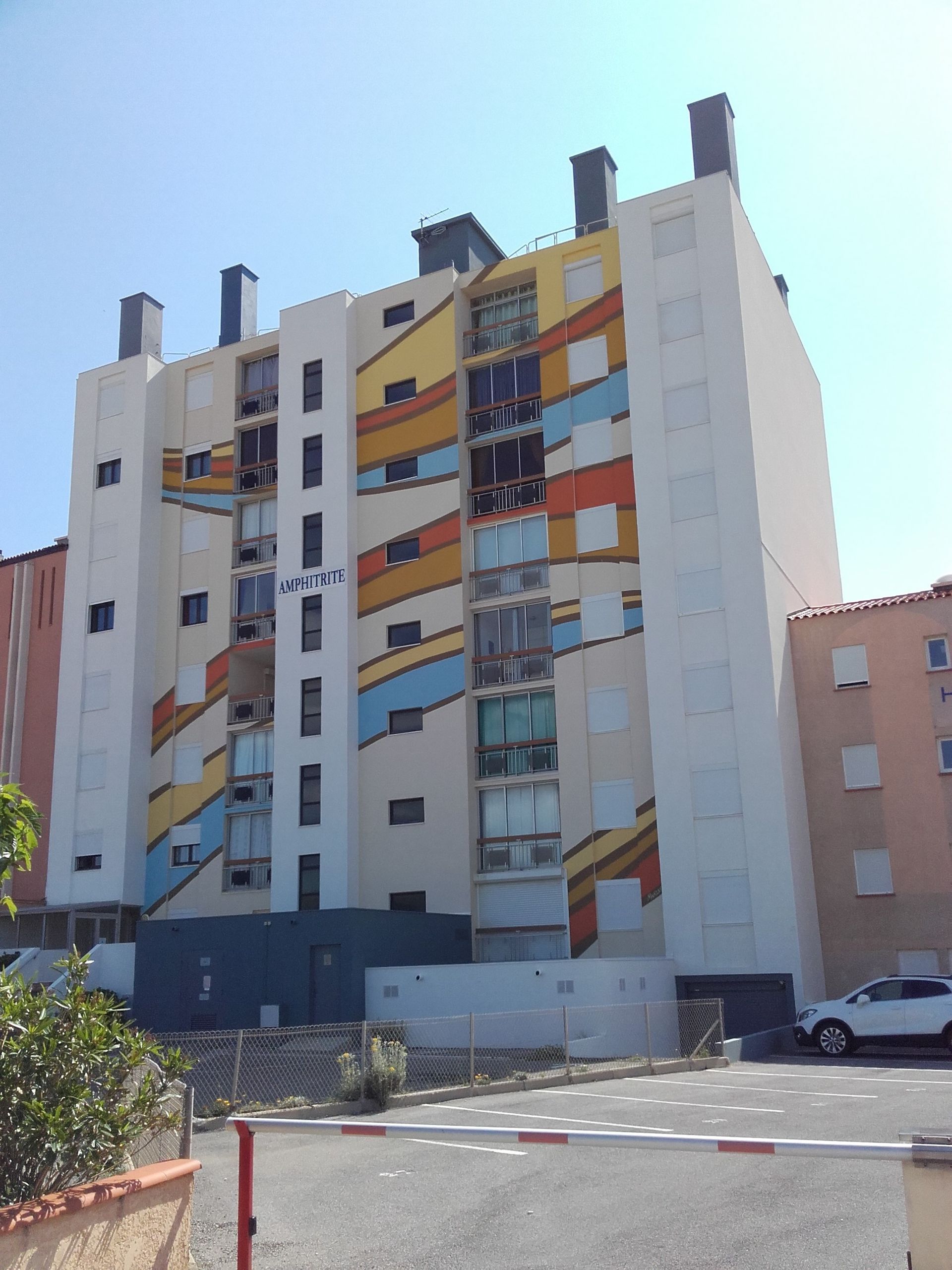 Un immeuble d'appartements à plusieurs étages, à la façade blanche ornée de motifs muraux abstraits, colorés